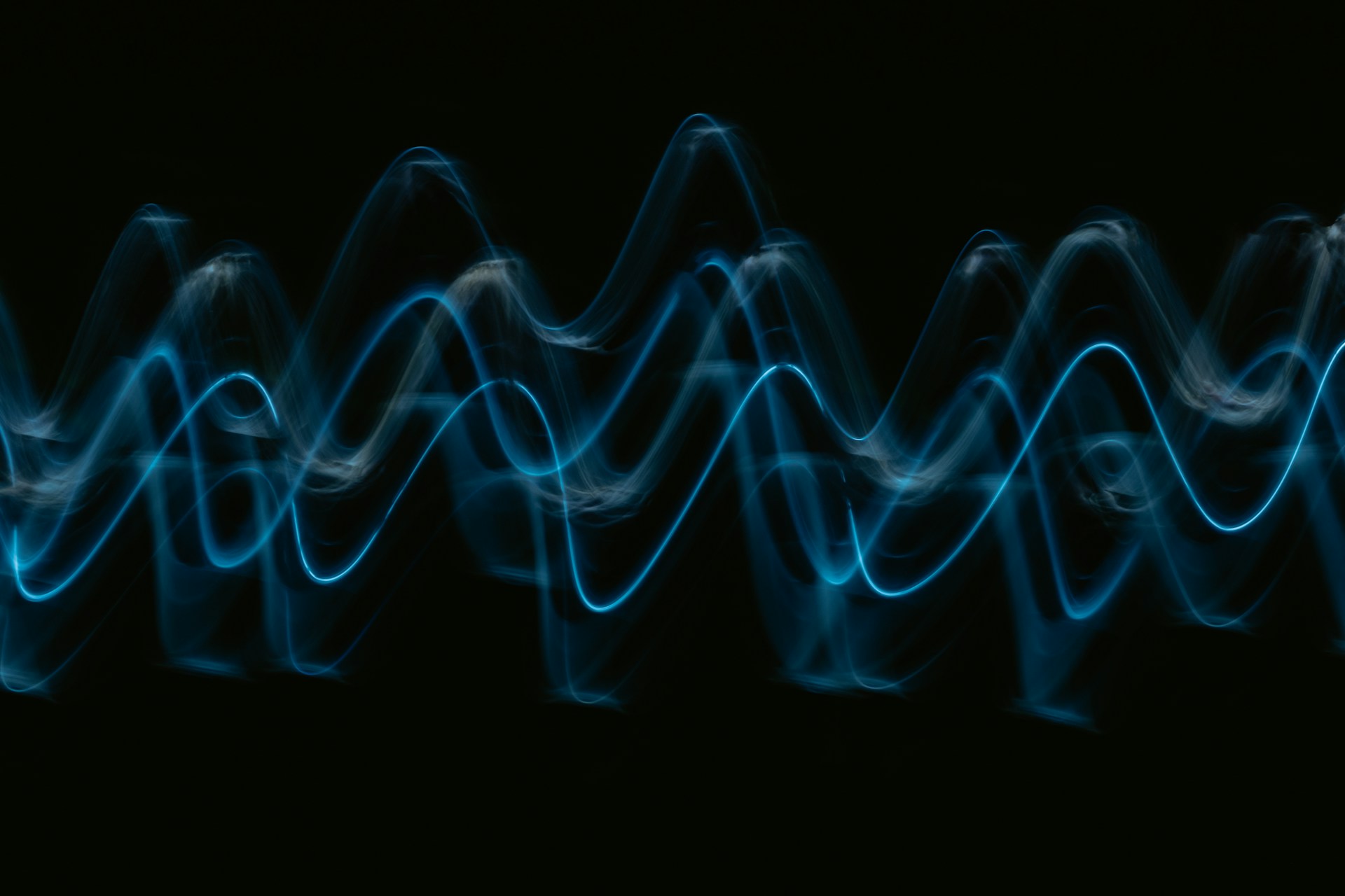 Abstract glowing blue sound wave on black background
